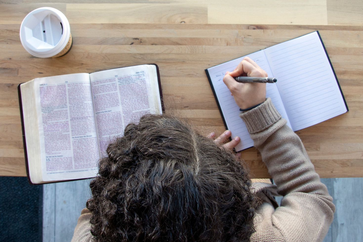 Top View of Person Studying Bible and Writing on Notebook